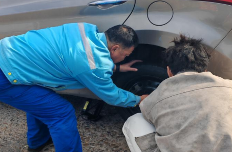 加油站员工帮助顾客更换故障轮胎 加油站员工帮助顾客更换故障轮胎