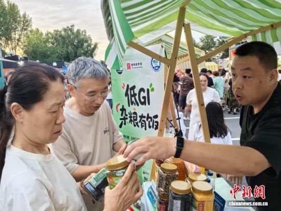 8月15日,长春新民大街,游客在吉林粮食品牌路演活动现场了解产品特点。李钊 摄 8月15日,长春新民大街,游客在吉林粮食品牌路演活动现场了解产品特点。李钊 摄